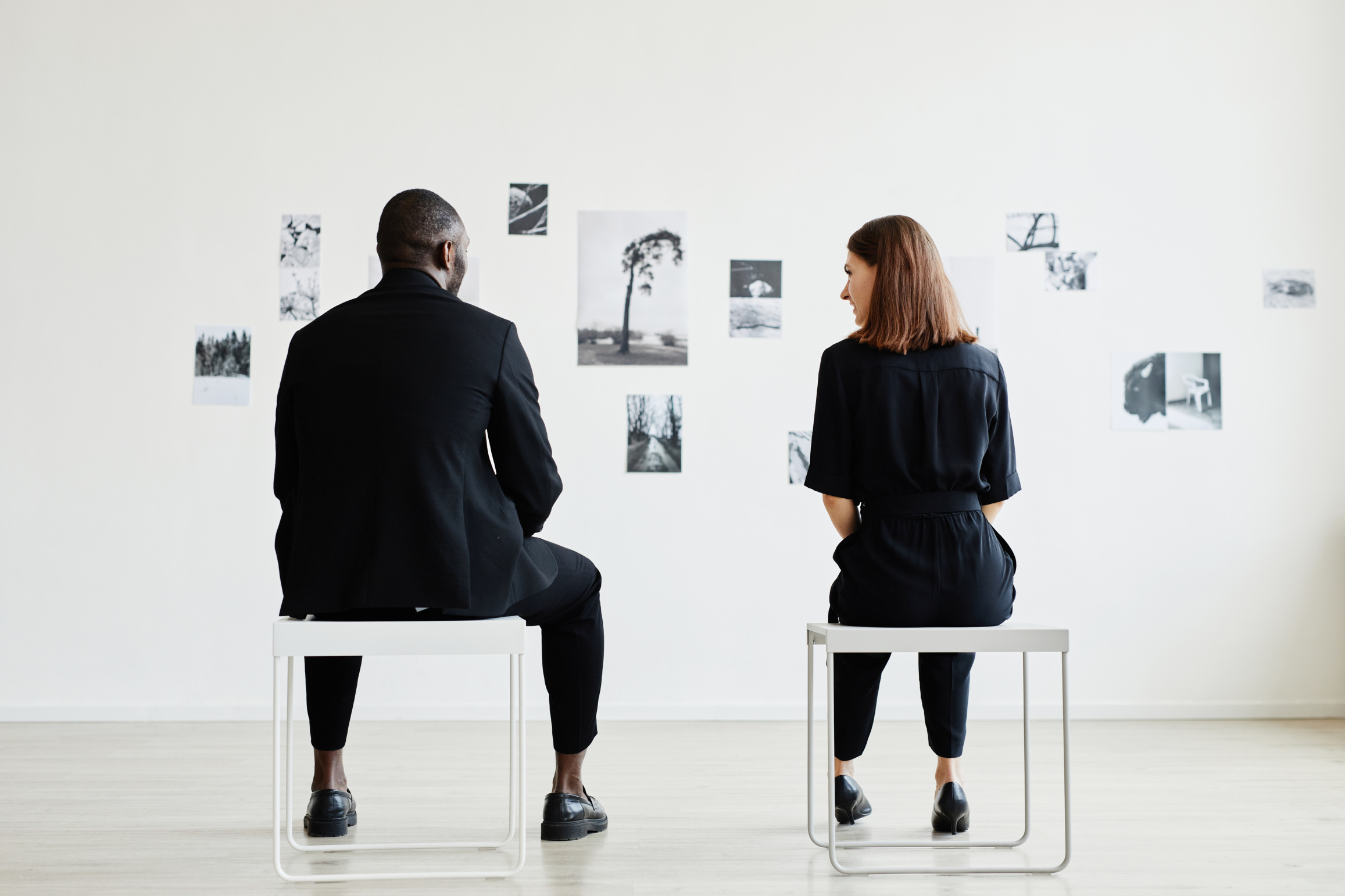 Full length back view at elegant couple looking at black and white photographs in modern art gallery, copy space