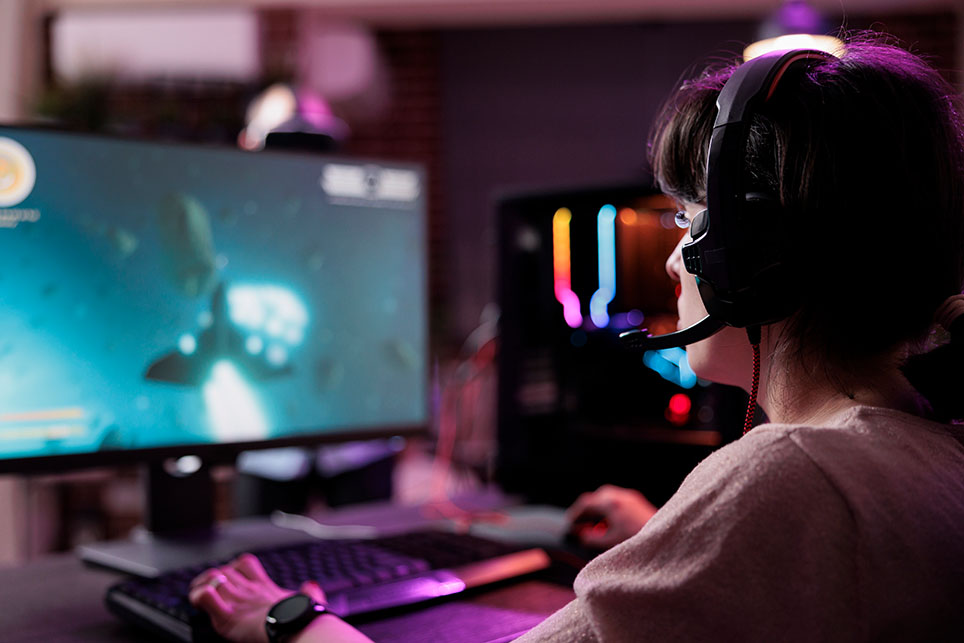 Young streamer playing video games online on live stream, using computer and neon lights in living room. Female gamer having fun with action gameplay on virtual shooting tournament.